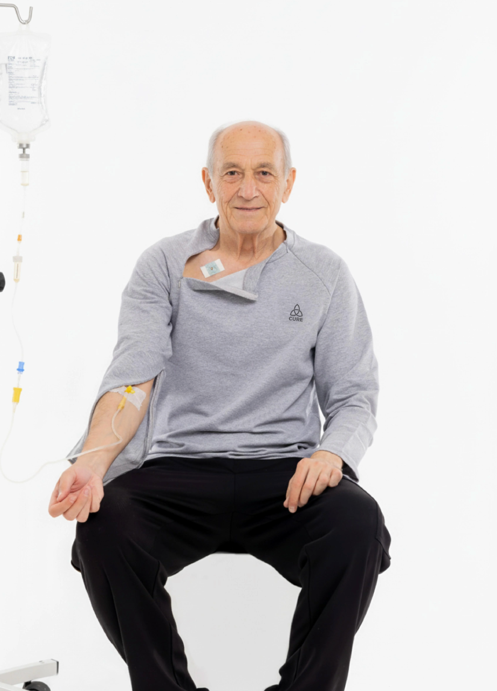 ComfortCure adaptif kemoterapi tedavi kıyafeti giyen erkek kullanıcı, oturur pozisyonda önden görünüm